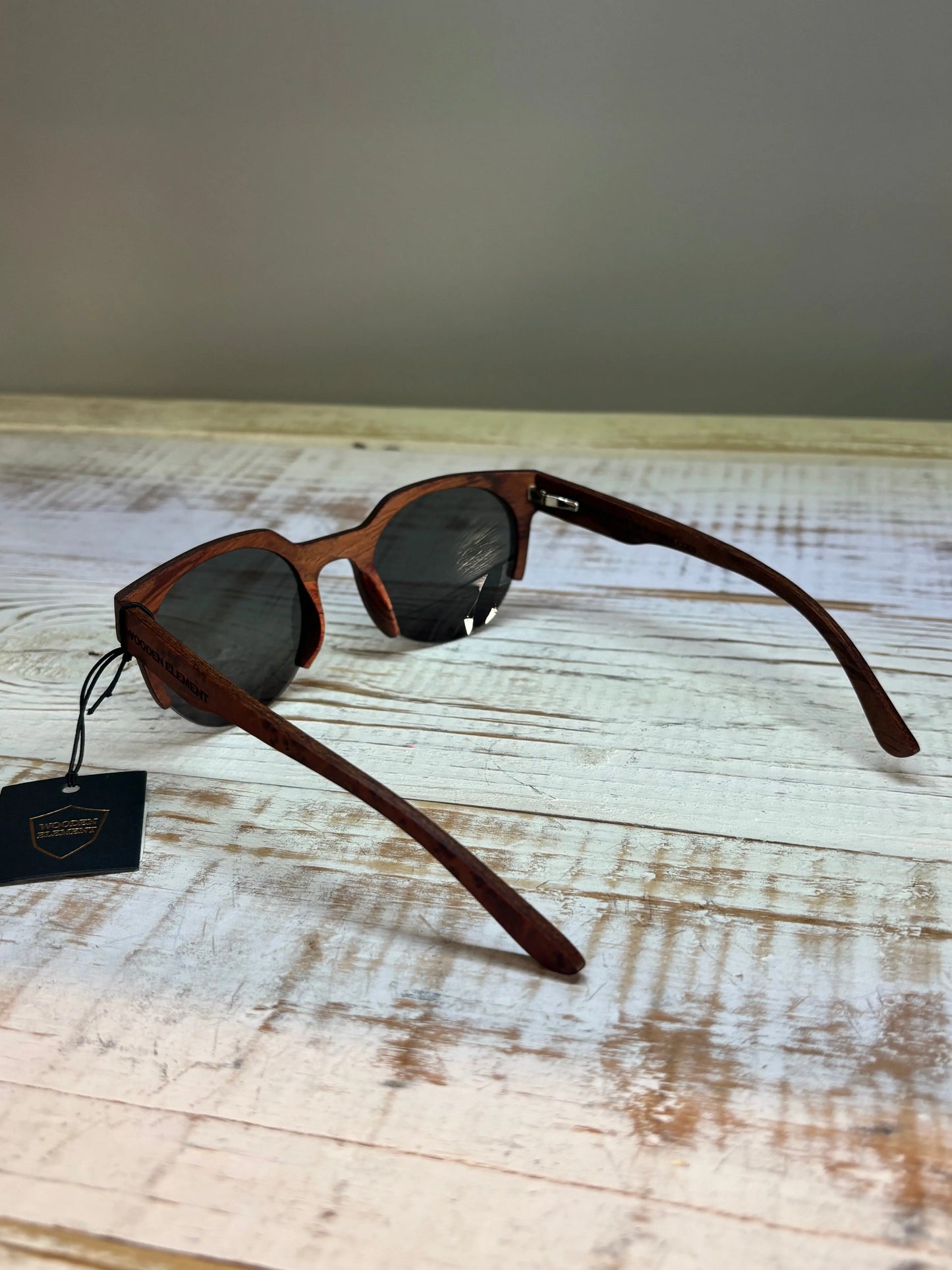 Wooden-framed sunglasses opened with a tag on a wooden surface