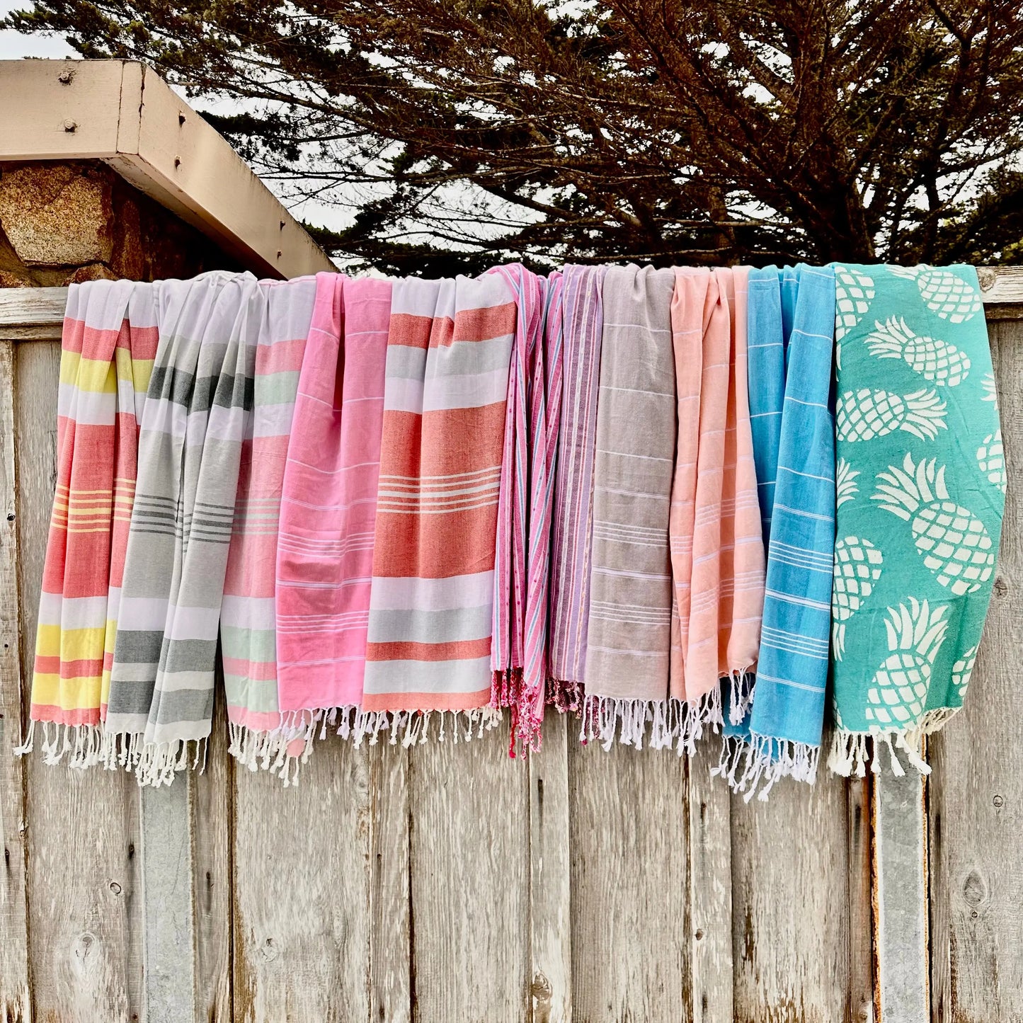 an assortment of towels hanging over a wood fence