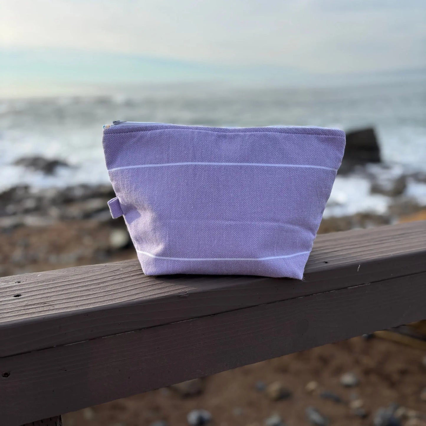 Purple fabric pouch on a wooden ledge with a blurred natural background