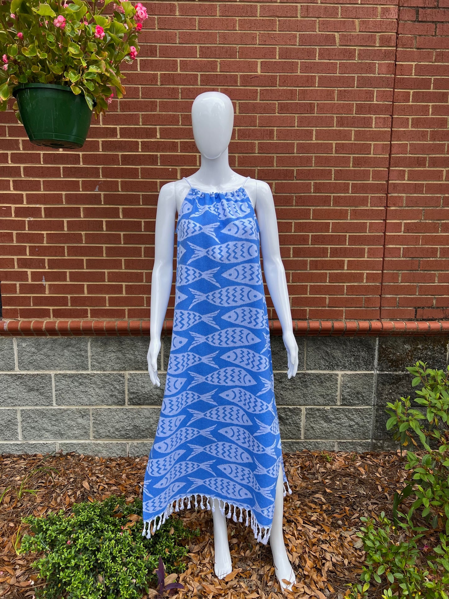 Mannequin wearing a blue and white fish print sleeveless maxi sundress with tassels in front of brick wall
