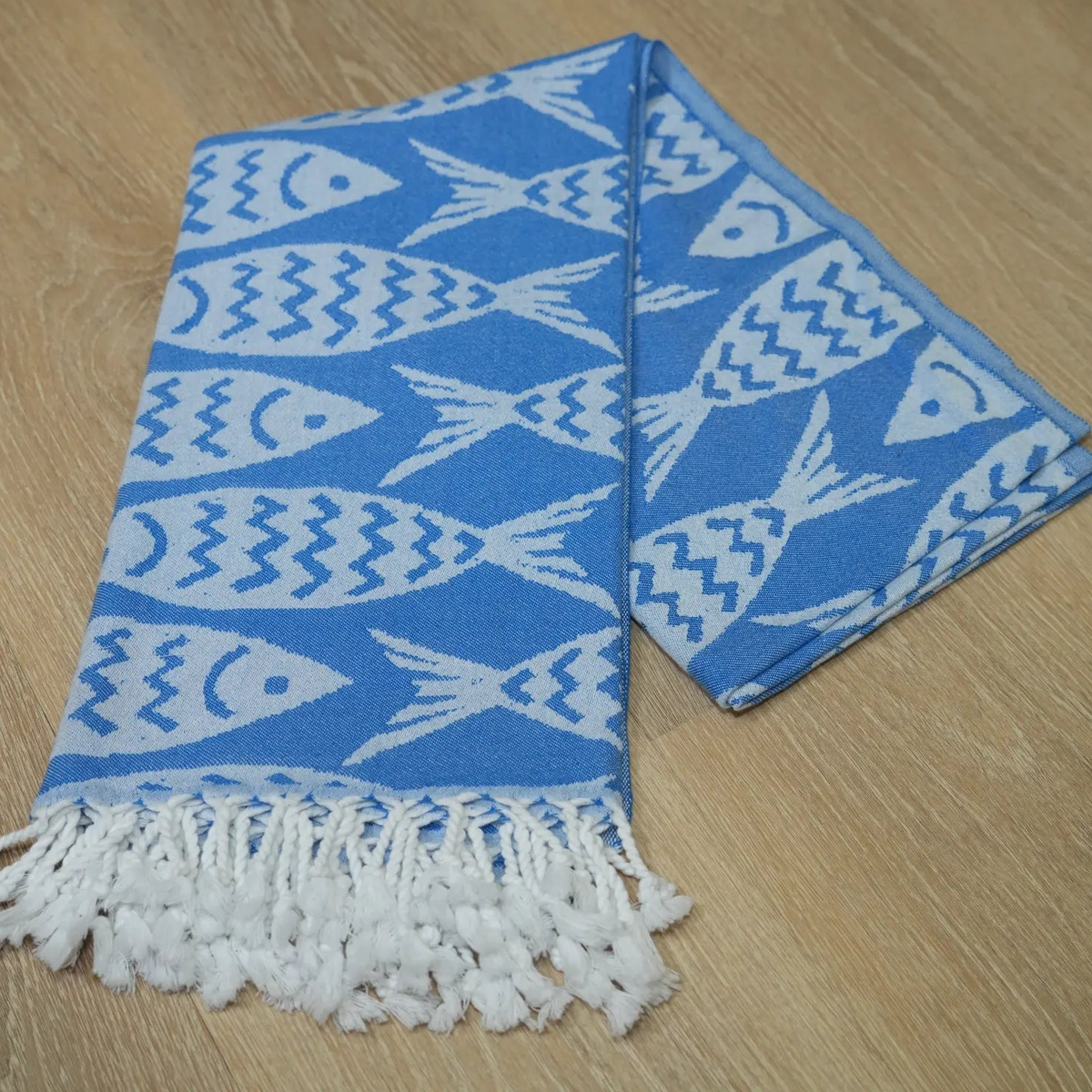 blue and white fish patterned towel folded laying on a wood surface