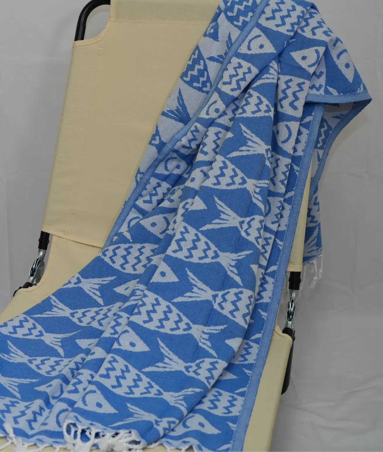 blue and white fish patterned towel draped over a lounge chair