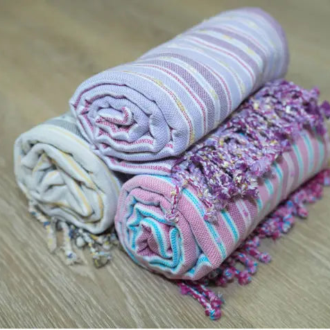stacked rolls of Turkish towels on wood surface