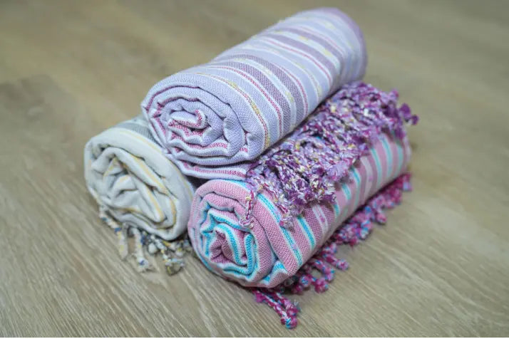 stacked rolls of Turkish towels on wood surface