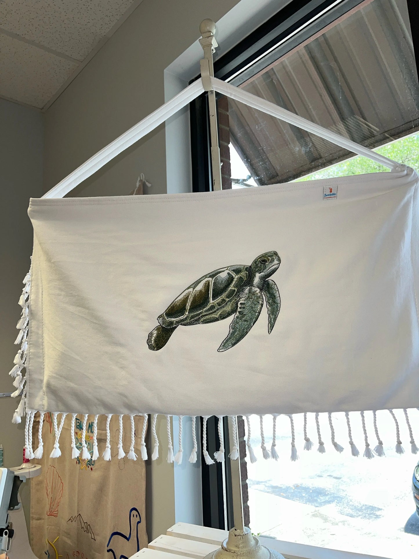 White bag with a turtle design hanging on a rack indoors