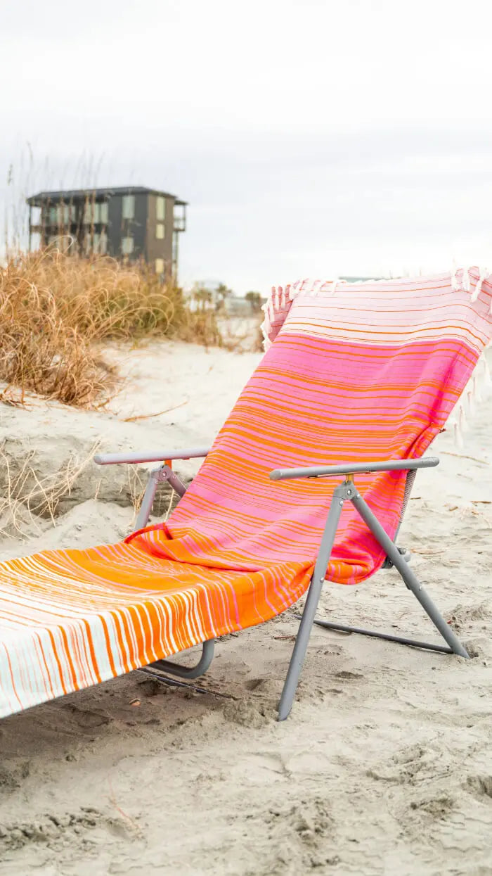 Colorful striped beach towel on a chair on a sandy beach with blurred background