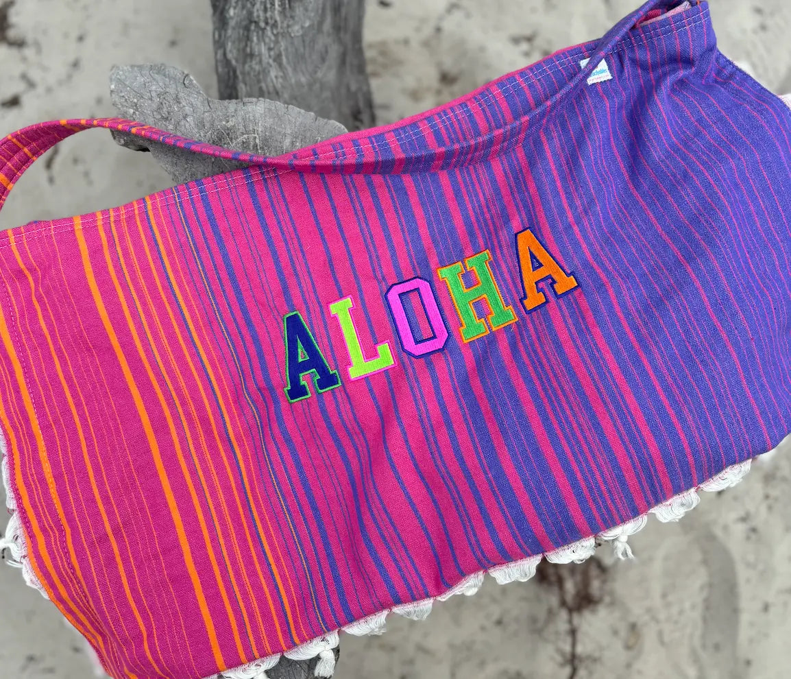 Colorful striped bag with 'ALOHA' text on a textured surface