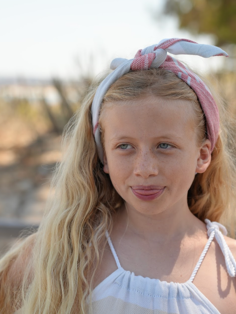Red, blue and white striped bandana being worn as a headband on young girl