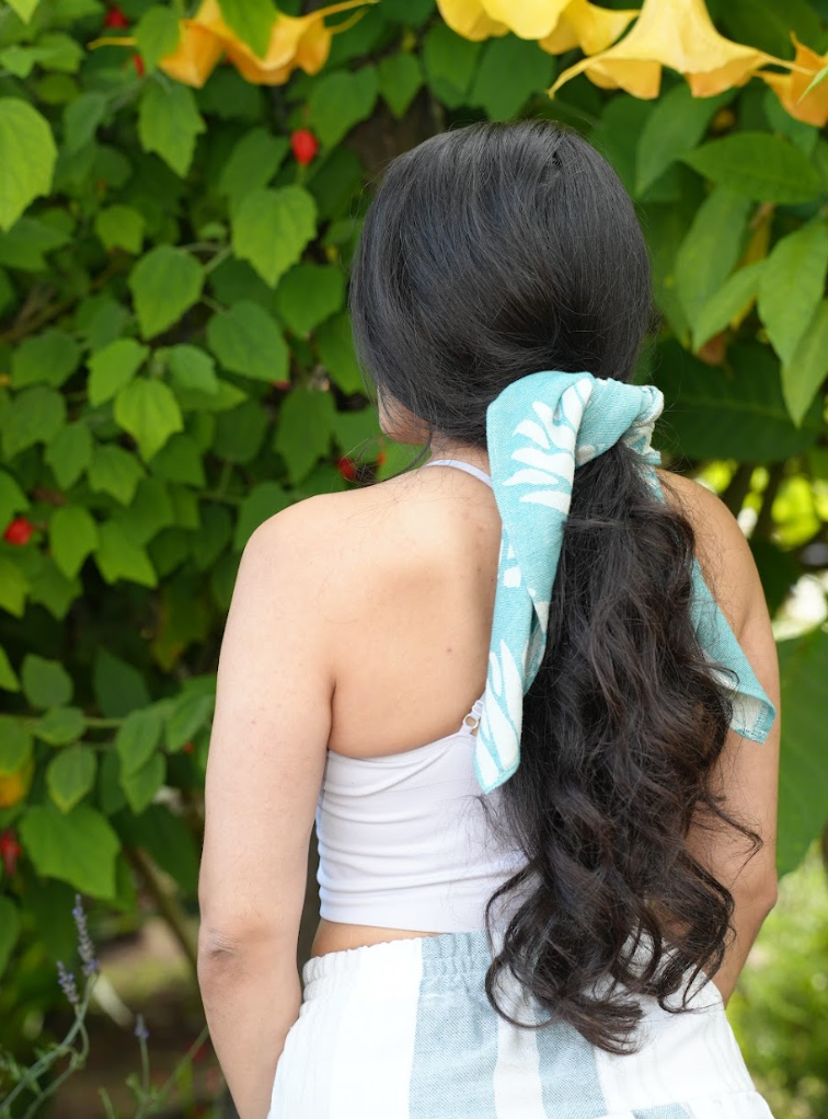 Green pineapple print bandana being worn as a hair tie for long hair