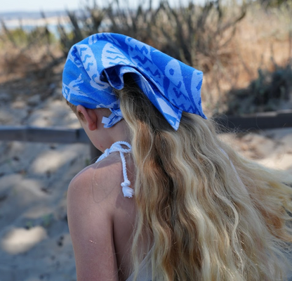 A person wearing a blue and white fish print bandana as a headband.