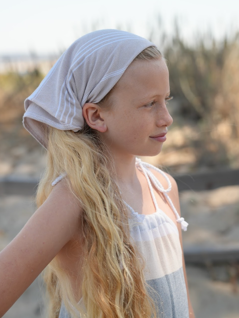 Tan striped bandana being worn as a headband on young girl