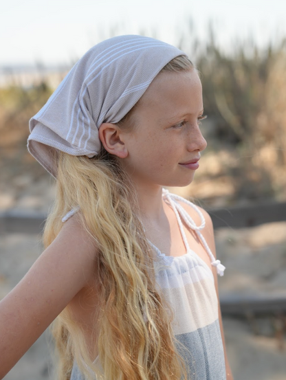 Tan striped bandana being worn as a headband on young girl