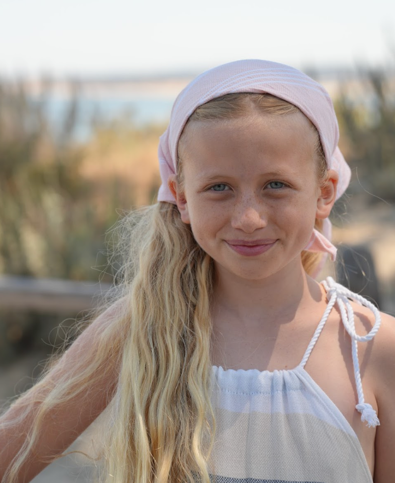 Peach striped bandana being worn as a headband on a young girl