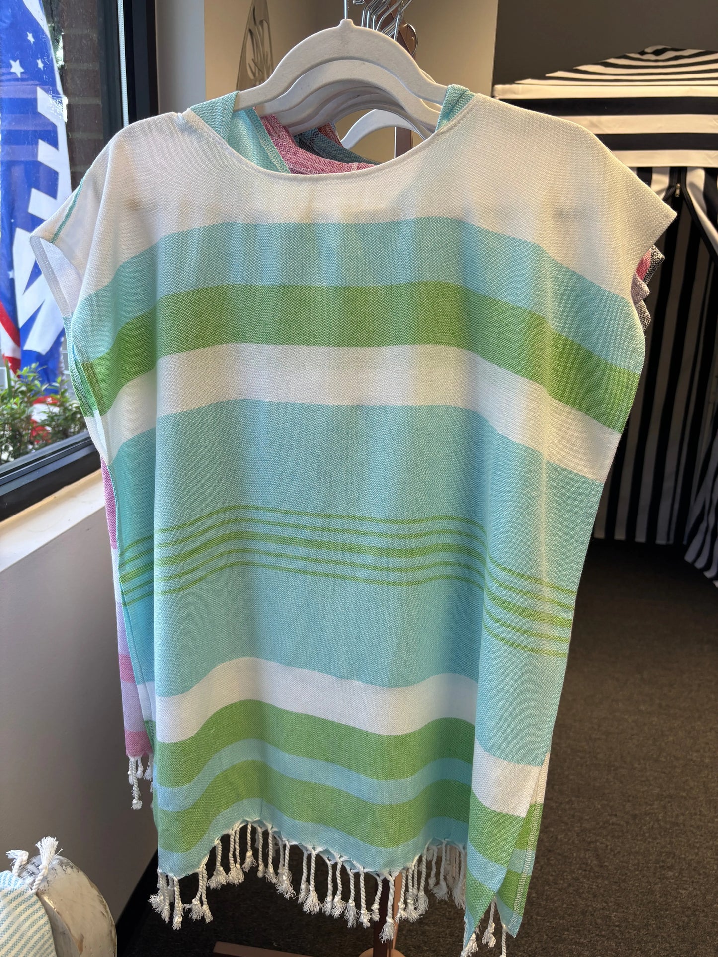  a poncho with blue, green and white stripes on a hanger