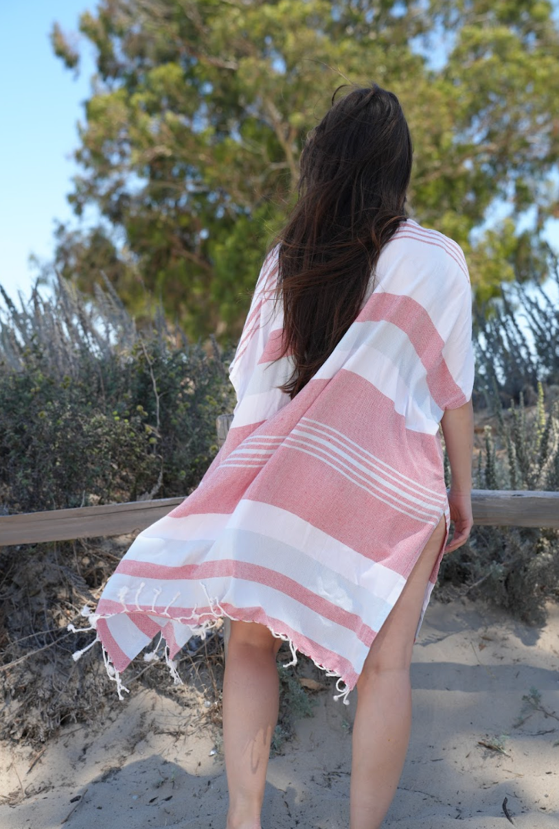 Back view of a woman in blue, red and white stripe mid-length cover-up in outdoor setting