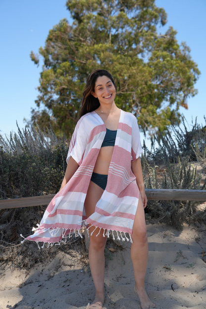 Woman in blue, red and white stripe mid-length cover-up over a bathing suit in outdoor setting