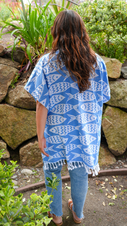 Back view of a woman in blue and white fish print mid-length cover-up in outdoor setting