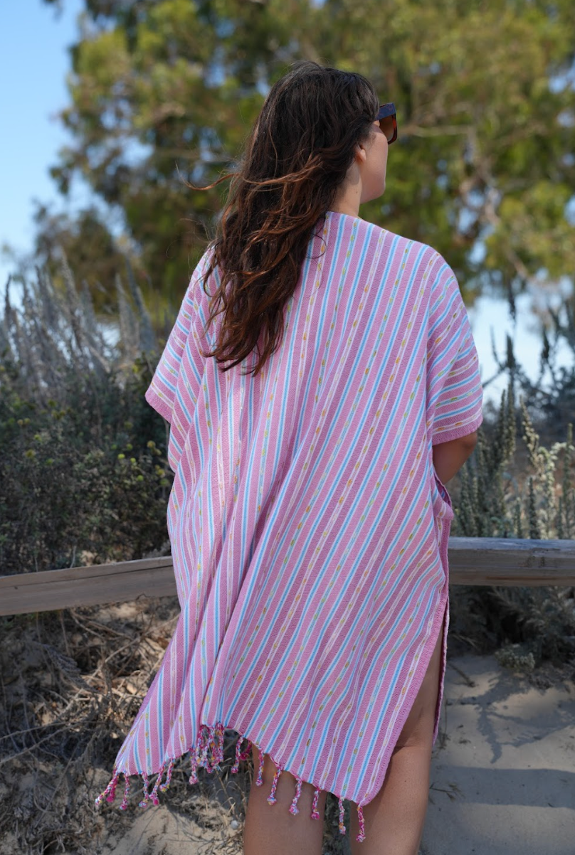 Back view of a woman in pink stripe mid-length cover-up in outdoor setting