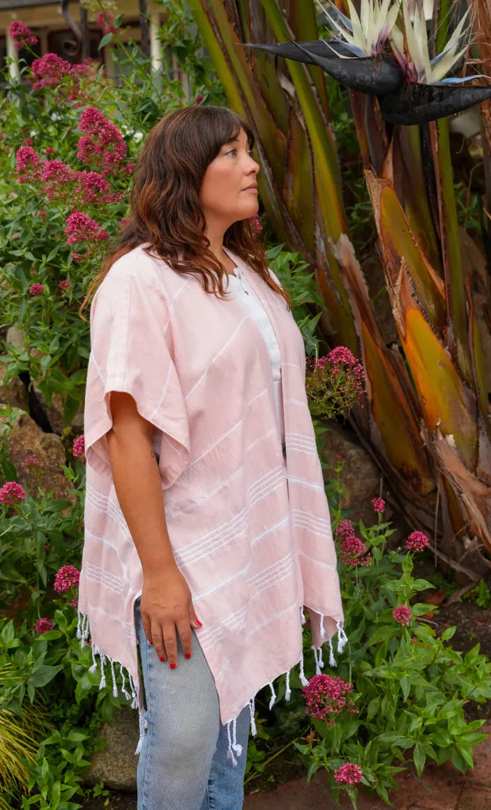 Woman wearing a peach wrap with tassels  in a garden setting