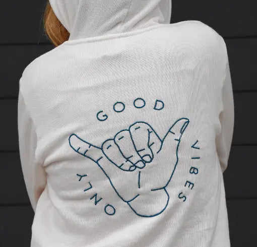 A white hoodie with 'GOOD VIBES' graphic embroidered on the back, featuring a hand making a hang loose sign.