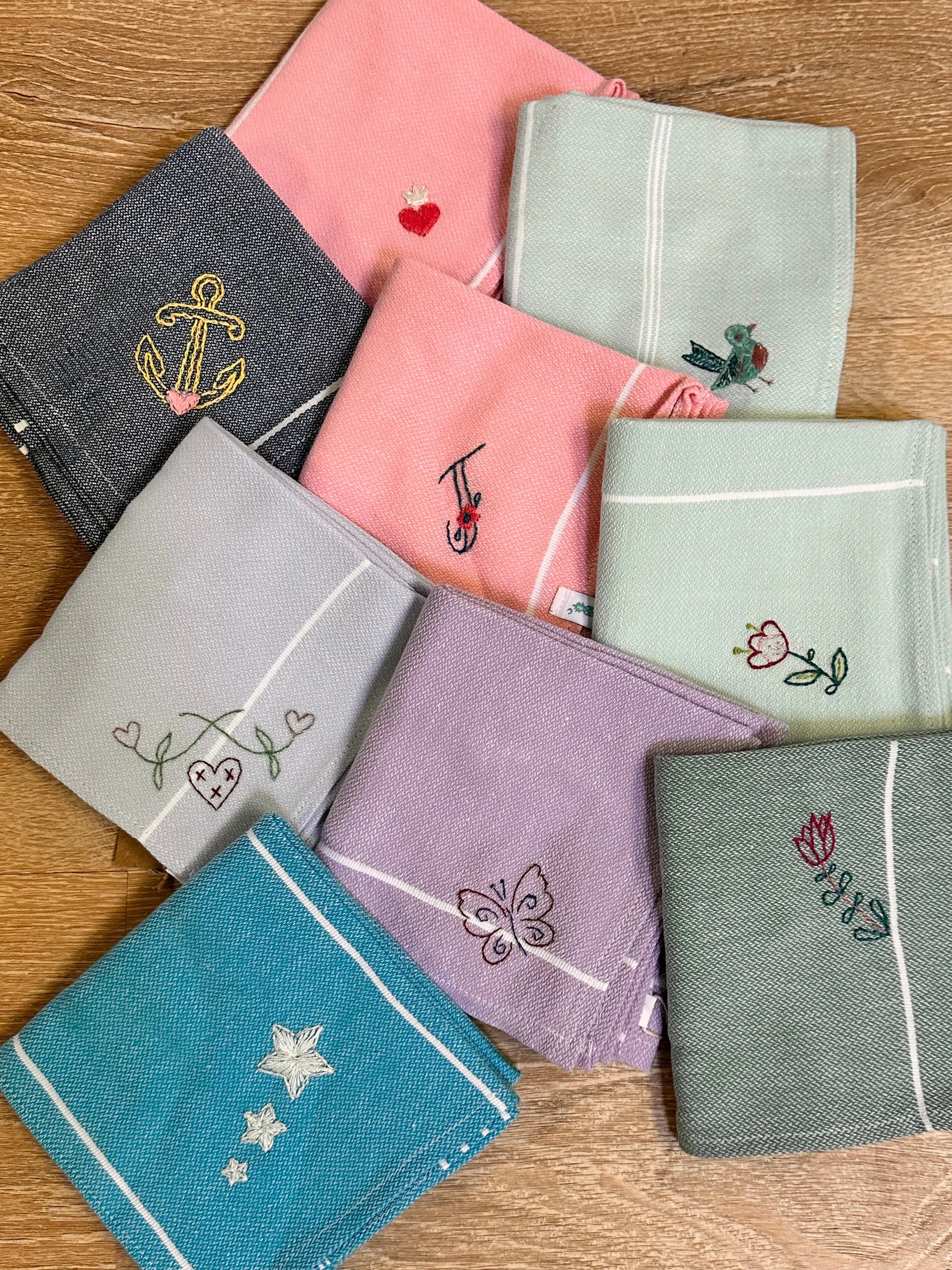 Collection of embroidered handkerchiefs in various colors on a wooden surface