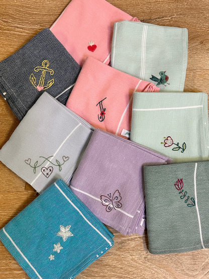 Collection of embroidered handkerchiefs in various colors on a wooden surface