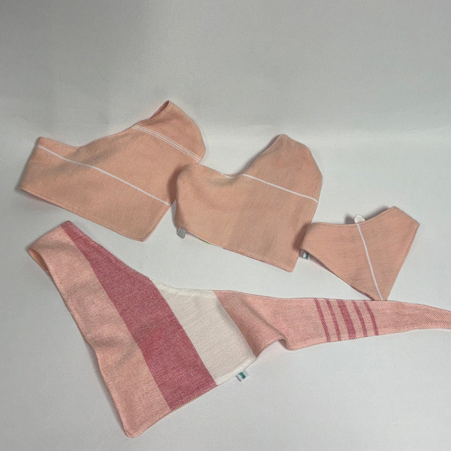 Three fabric headbands in dusty pink, terracotta, and cream, laid out on a light gray background.