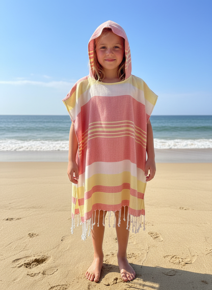 Child wearing a colorful red and yellow hooded poncho on a beach