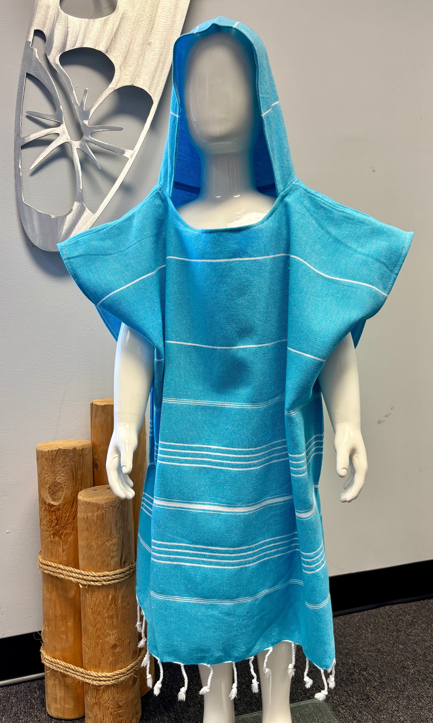 A child mannequin wearing a blue striped hooded sun poncho with tassel detailing