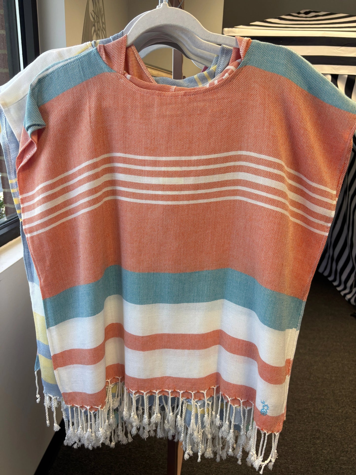 hooded poncho on a hanger with turquoise, orange and white stripes