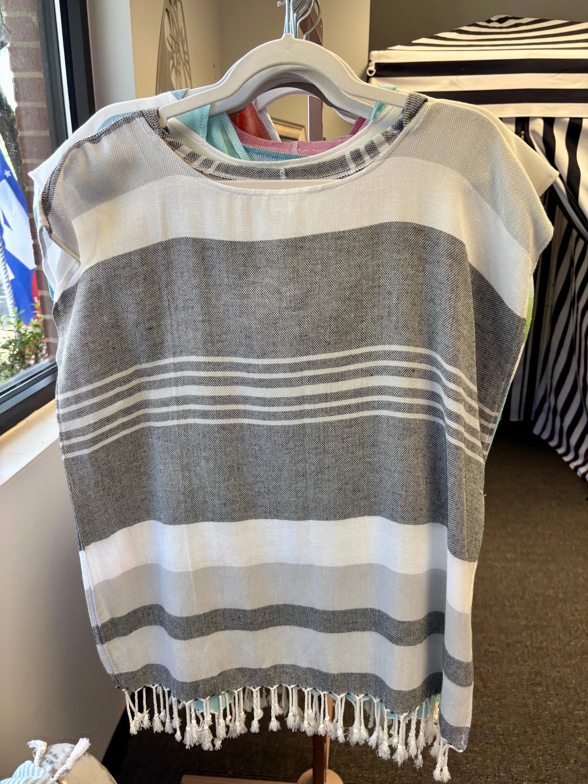 hooded poncho on a hanger with grey, charcoal and white stripes