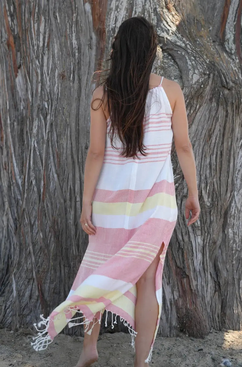 Woman wearing a red, yellow and white striped dress standing against a textured wall.