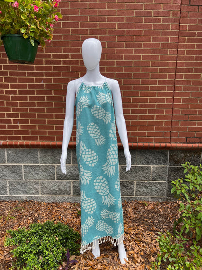 Mannequin wearing green pineapple print sleeveless maxi sundress with tassels in front of brick wall 