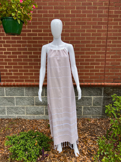 Mannequin wearing tan striped sleeveless maxi sundress with tassels in front of brick wall 