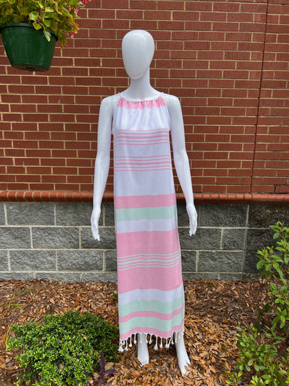 Mannequin wearing pink, green and white  striped sleeveless maxi sundress with tassels in front of brick wall 