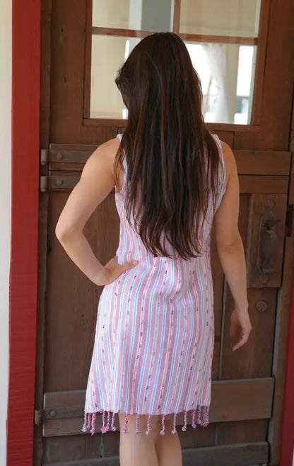 Back View of a woman standing outdoors wearing a pink striped sleeveless knee-length dress with  tassels.