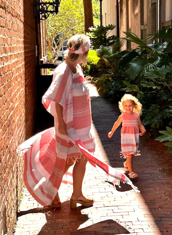 Woman and child walking on a sidewalk with a red , blue and white striped kimono wrap and matching dress.