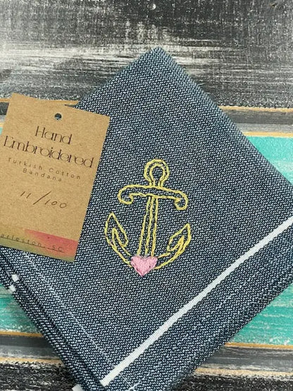 Hand embroidered fabric with anchor design and pink heart, on a textured surface.