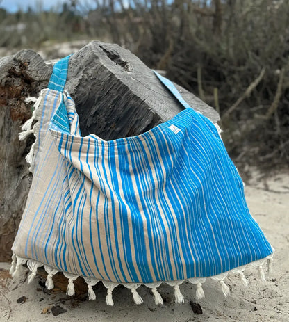 Blue and beige striped bag with tassels on a sandy background