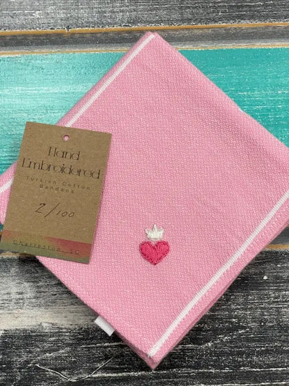 Pink hand-embroidered napkin with a heart design on a wooden surface