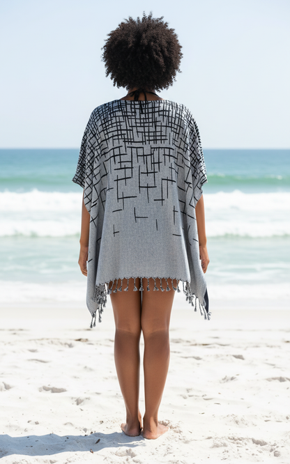 Person wearing a black and white patterned cover-up on a beach with ocean view