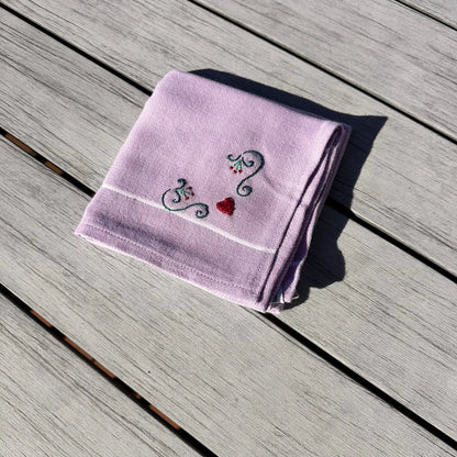 Folded purple towel with embroidered designs on a wooden surface