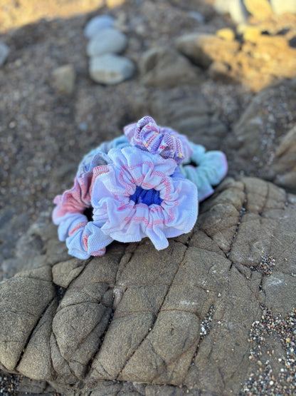 a small pile of colorful scrunchies on a textured stone surface
