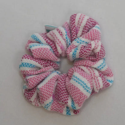Pink, white, and blue striped scrunchie on a light gray background