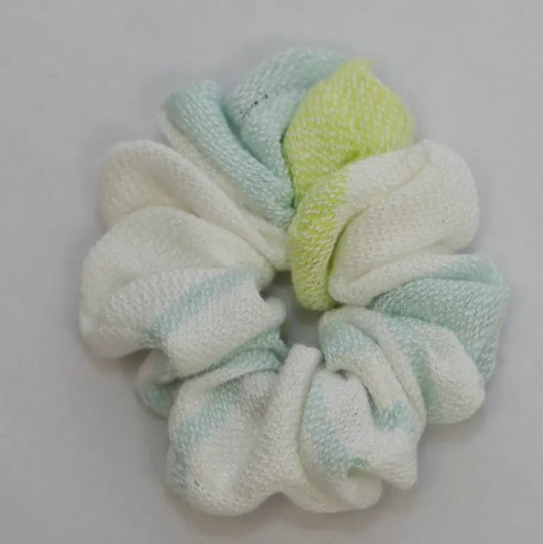 Textured scrunchie in light green and white on a gray background