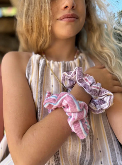 young girl  holding pink and white scrunchies with a blurred background