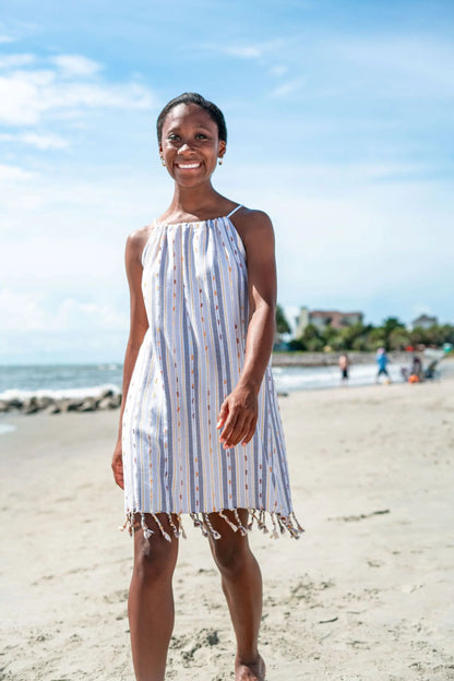 Woman walking on beach wearing a sleeveless brown striped cover-up 