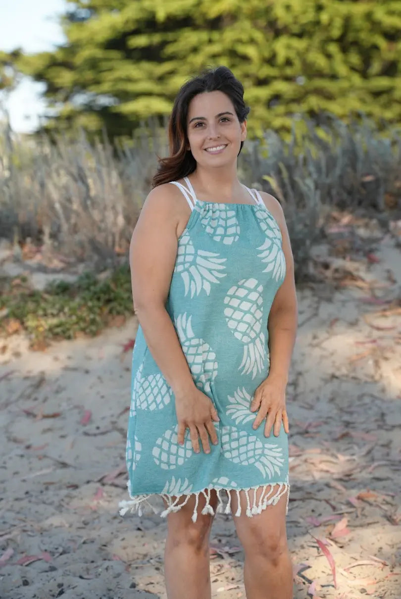 Woman on beach wearing a sleeveless green pineapple print cover-up  with tassels