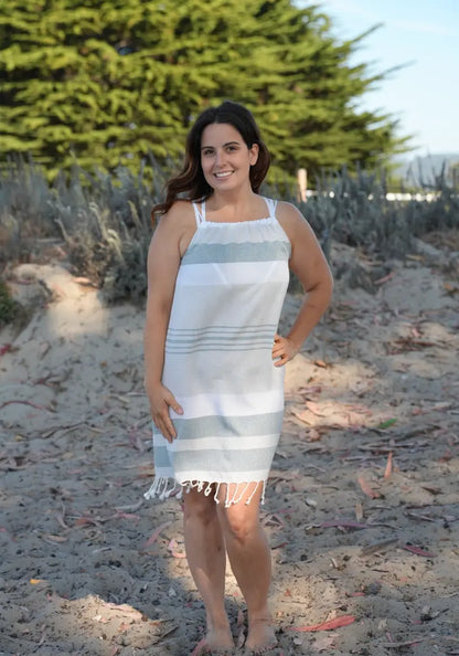 Woman on beach wearing a sleeveless charcoal, grey and white striped cover-up  with tassels