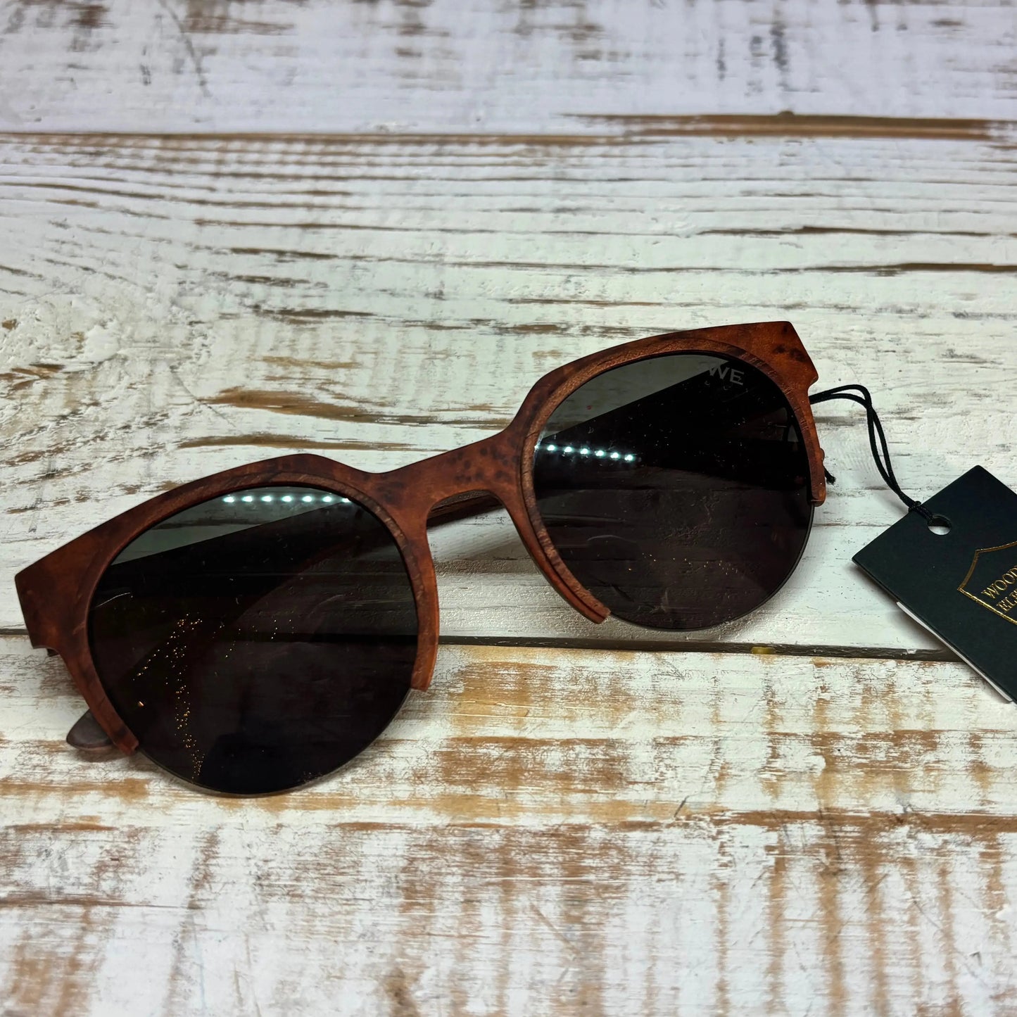 Wooden-framed sunglasses with a tag on a wooden surface